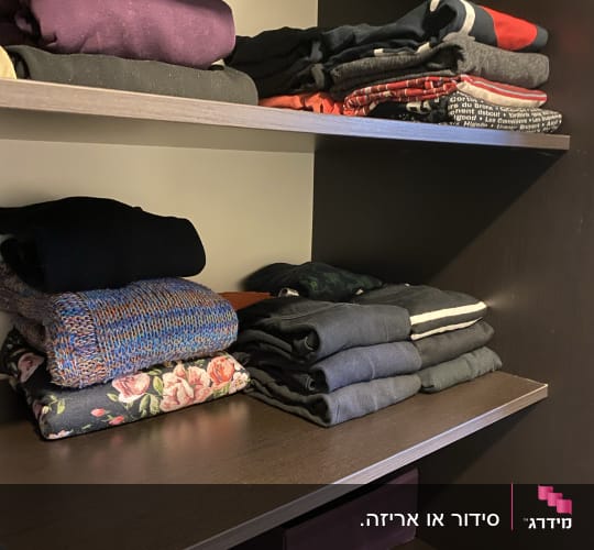 בגדים מקופלים על מדפים בארון כהה